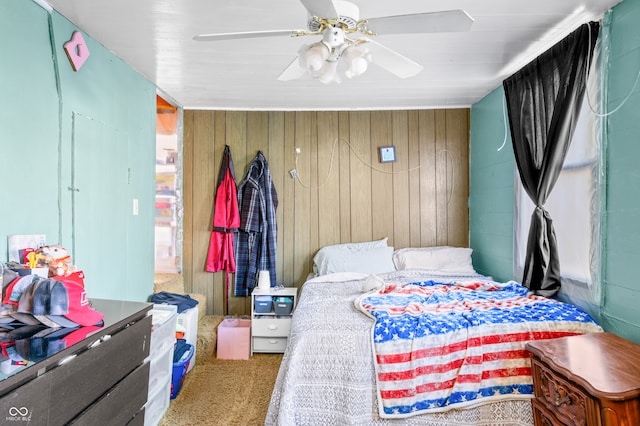 carpeted bedroom featuring ceiling fan and wood walls