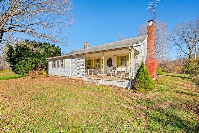 back of house with covered porch and a lawn