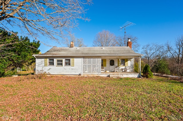 rear view of house featuring a lawn and a porch