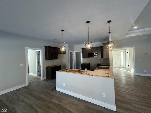 kitchen featuring dark wood-type flooring, dark brown cabinetry, and decorative light fixtures