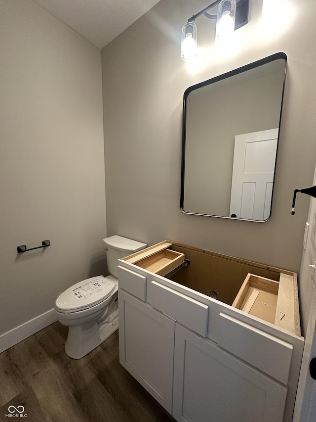 bathroom with hardwood / wood-style flooring, vanity, and toilet