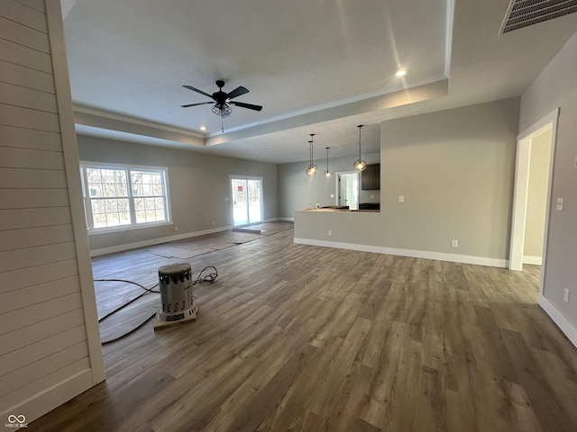 unfurnished living room with hardwood / wood-style flooring, ceiling fan, ornamental molding, and a raised ceiling