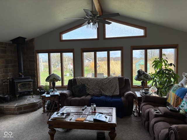 carpeted living room featuring lofted ceiling, a wood stove, ceiling fan, and plenty of natural light