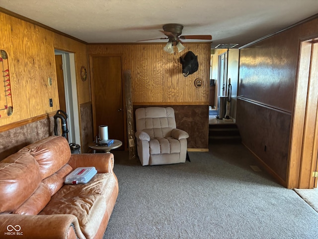 carpeted living room featuring crown molding, wooden walls, and ceiling fan