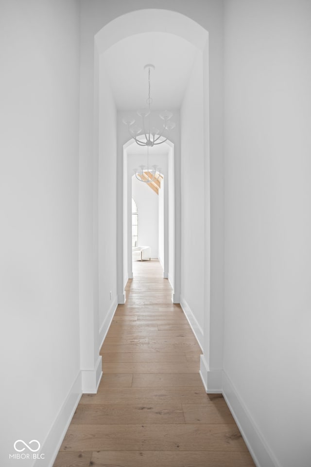 corridor with light hardwood / wood-style flooring and a chandelier