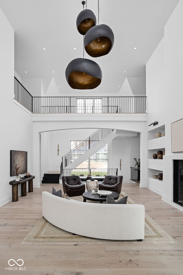 living room with a high ceiling, light hardwood / wood-style flooring, and built in shelves