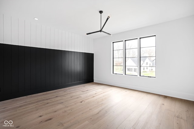 unfurnished room with light hardwood / wood-style floors and wooden walls