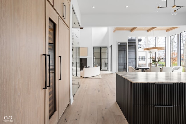 kitchen with beam ceiling, an inviting chandelier, fridge, and light hardwood / wood-style flooring