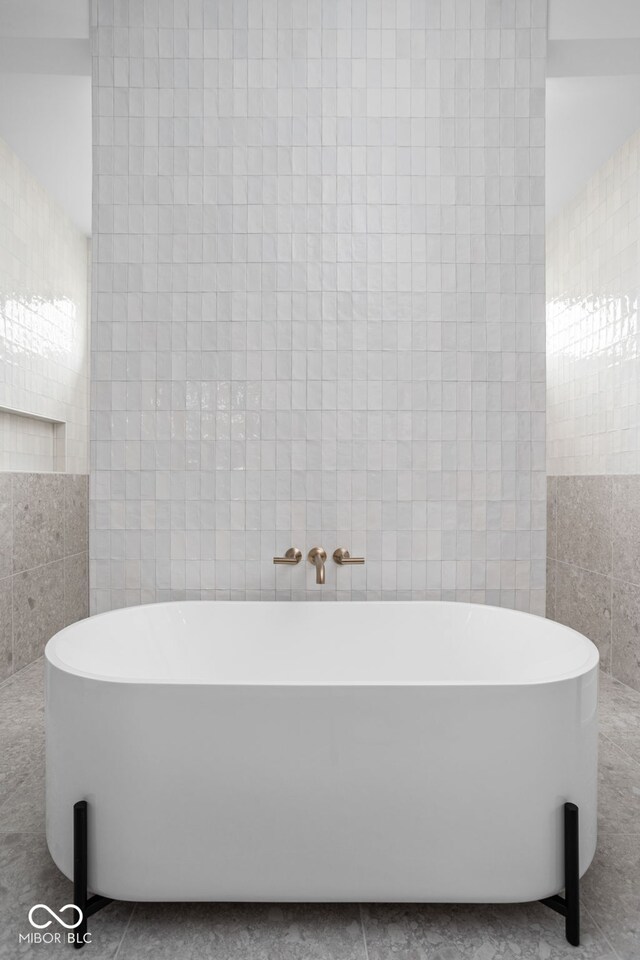 bathroom with tile patterned floors, a bathing tub, and tile walls