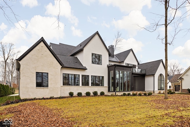 rear view of property with a lawn and a sunroom