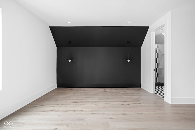 spare room featuring light hardwood / wood-style flooring and lofted ceiling