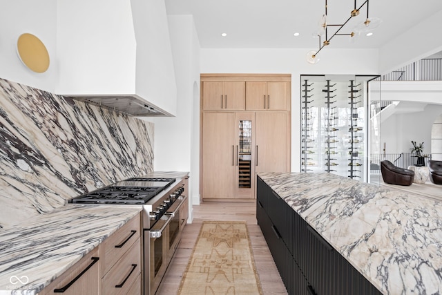 kitchen with light brown cabinets, light hardwood / wood-style flooring, double oven range, and light stone counters