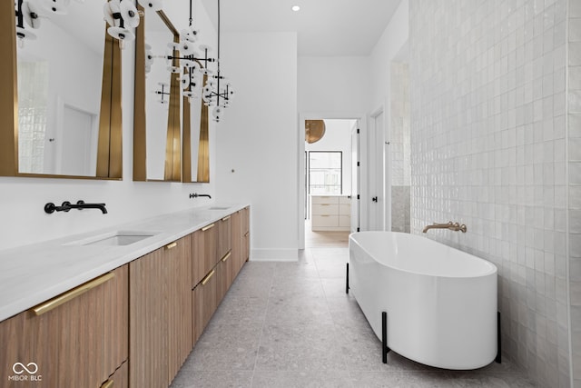 bathroom featuring tile patterned floors, a tub, vanity, and tile walls