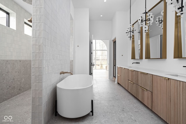 bathroom featuring plenty of natural light, separate shower and tub, tile walls, and vanity