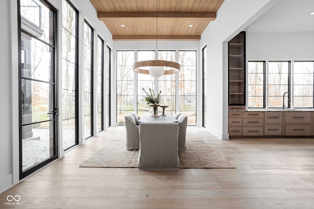 dining room with beam ceiling, wood ceiling, sink, and light hardwood / wood-style flooring