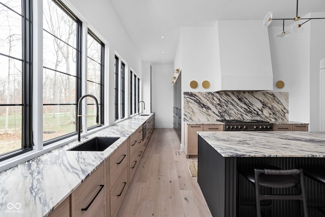 kitchen featuring a large island, sink, tasteful backsplash, light stone counters, and light hardwood / wood-style floors