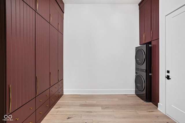 washroom featuring cabinets, light hardwood / wood-style flooring, and stacked washing maching and dryer