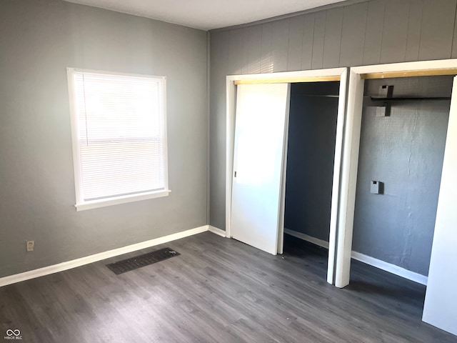 unfurnished bedroom featuring a closet and dark hardwood / wood-style floors