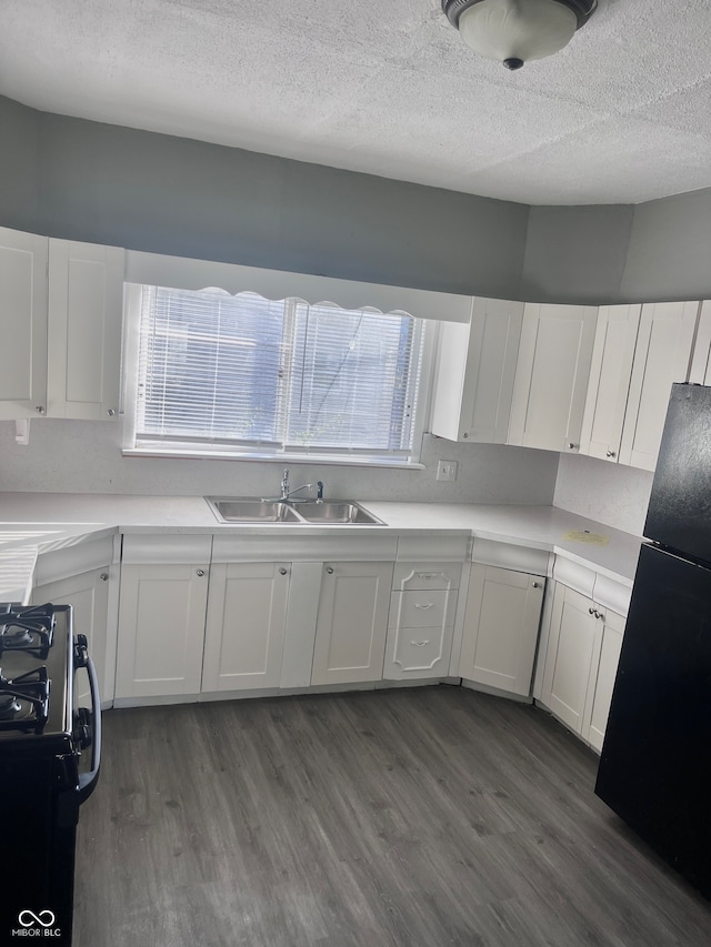 kitchen with white cabinets, dark hardwood / wood-style floors, black fridge, and stainless steel range