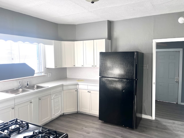 kitchen with black appliances, a textured ceiling, sink, hardwood / wood-style floors, and white cabinets