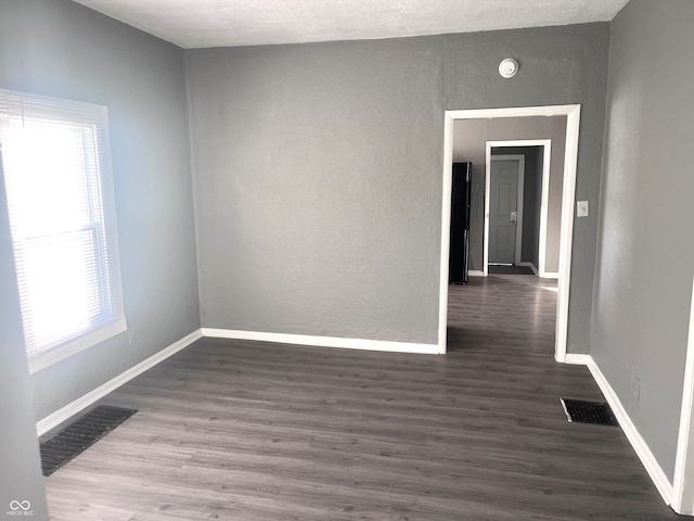 spare room featuring dark wood-type flooring and a textured ceiling