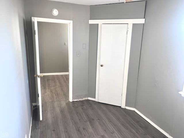 unfurnished bedroom featuring dark wood-type flooring and a closet