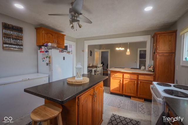 kitchen featuring ceiling fan, a breakfast bar area, light tile patterned floors, white appliances, and a center island