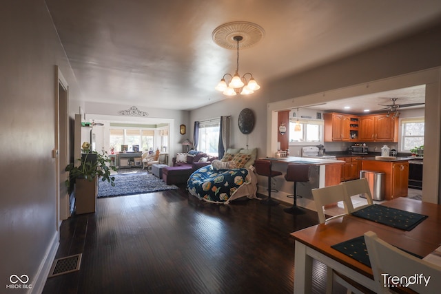 living room with ceiling fan with notable chandelier, dark wood-type flooring, a healthy amount of sunlight, and sink