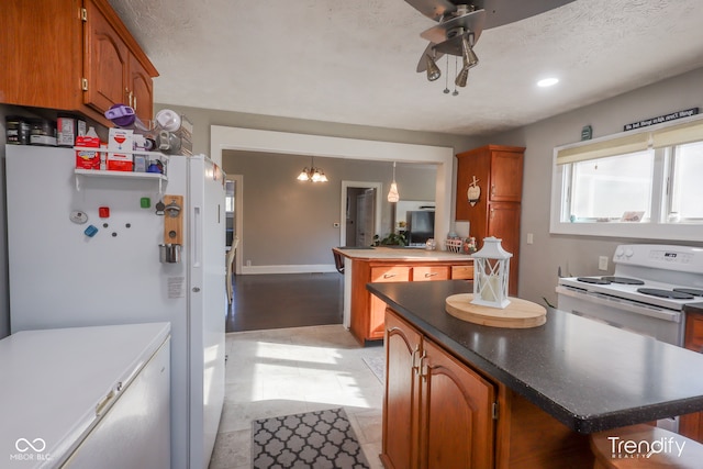 kitchen with white appliances, ceiling fan with notable chandelier, a textured ceiling, and a center island