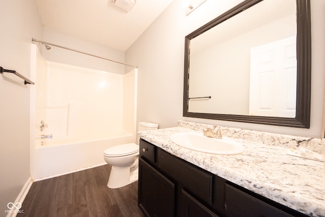 full bathroom with bathing tub / shower combination, a textured ceiling, wood-type flooring, vanity, and toilet