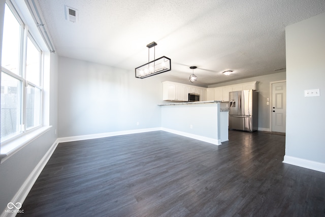 unfurnished living room featuring dark hardwood / wood-style flooring and a textured ceiling