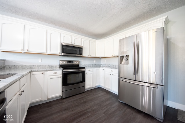 kitchen with white cabinets, a textured ceiling, dark hardwood / wood-style floors, light stone countertops, and appliances with stainless steel finishes