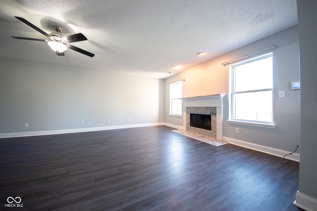 unfurnished living room with a textured ceiling, a wealth of natural light, and dark hardwood / wood-style floors