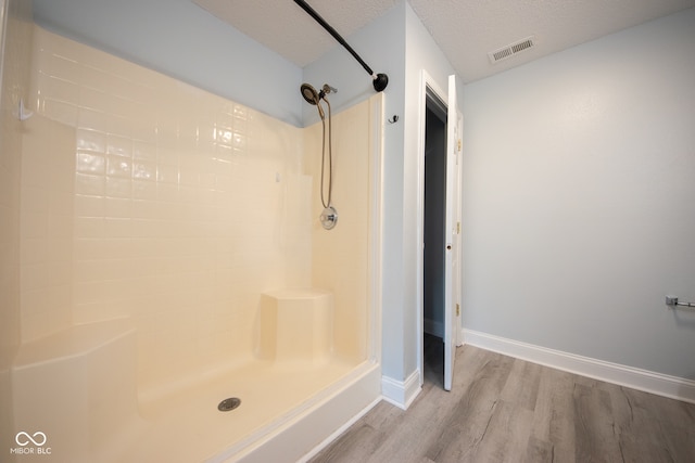 bathroom featuring walk in shower, hardwood / wood-style floors, and a textured ceiling