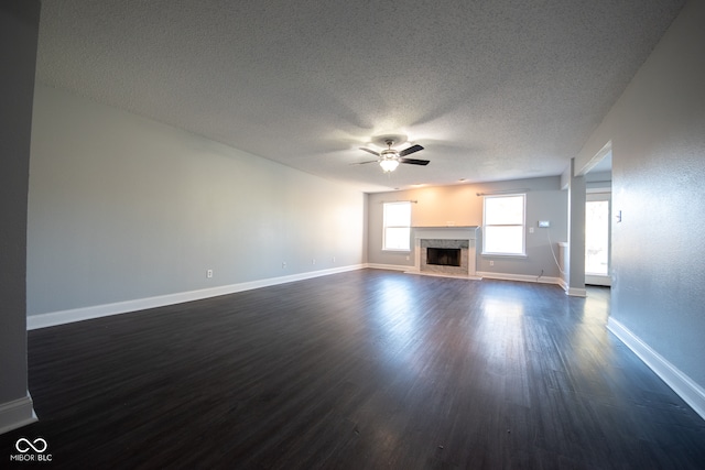 unfurnished living room featuring dark wood-type flooring, a textured ceiling, a high end fireplace, and ceiling fan