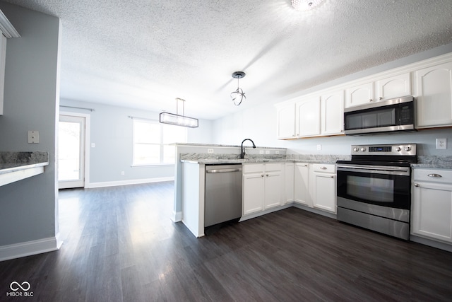 kitchen with hanging light fixtures, a textured ceiling, dark hardwood / wood-style floors, white cabinetry, and appliances with stainless steel finishes