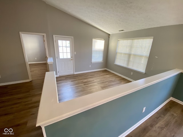 foyer with lofted ceiling, hardwood / wood-style floors, and a textured ceiling