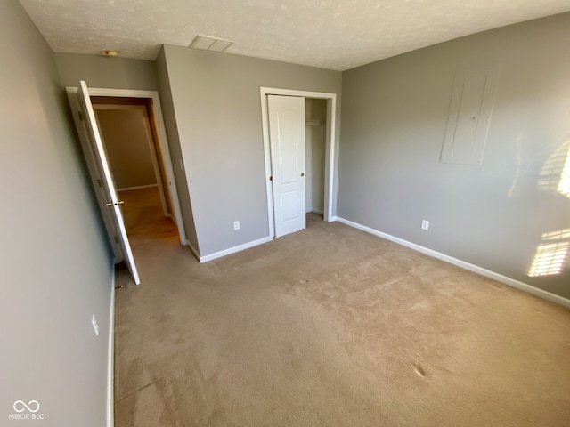 unfurnished bedroom featuring light colored carpet, a textured ceiling, and a closet