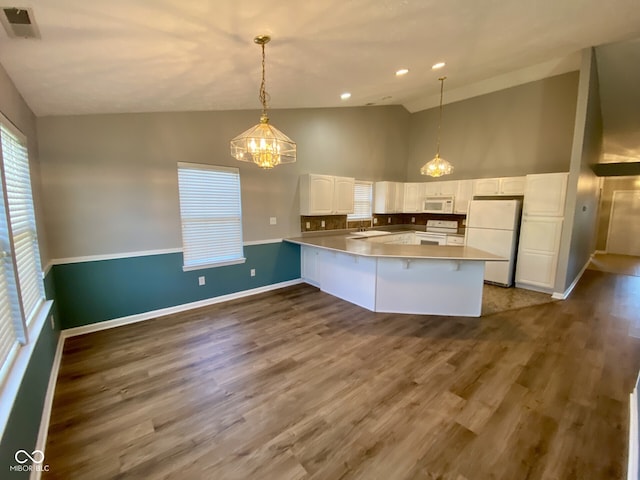 kitchen featuring vaulted ceiling, dark hardwood / wood-style floors, white cabinetry, white appliances, and decorative light fixtures