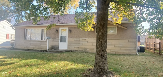 view of front of home with central air condition unit and a front lawn