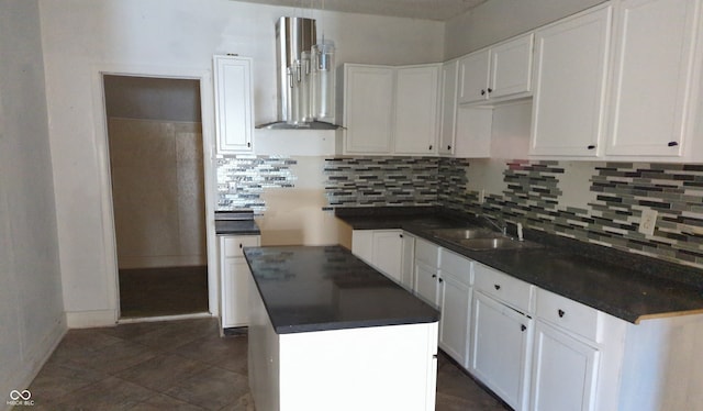 kitchen with decorative backsplash, sink, wall chimney range hood, a kitchen island, and white cabinetry