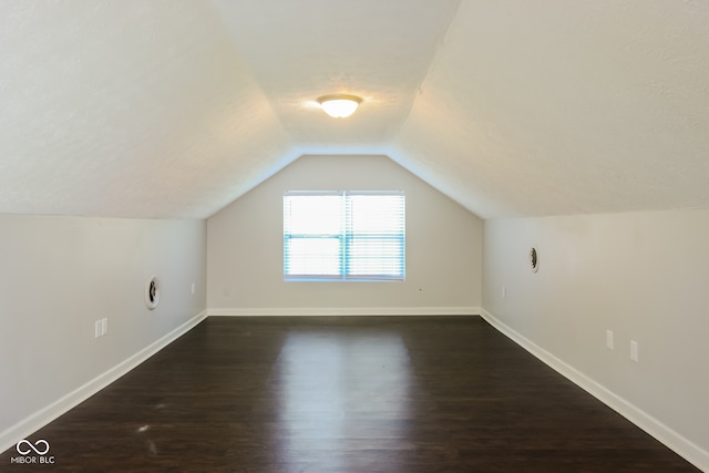 additional living space with dark hardwood / wood-style flooring and vaulted ceiling