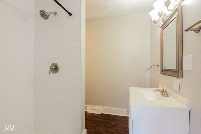 bathroom featuring a tile shower, hardwood / wood-style floors, vanity, and a textured ceiling