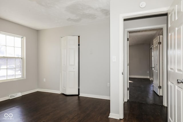 5060 Staughton Dr, Indianapolis, IN 46226 - unfurnished bedroom with dark wood-style flooring, baseboards, a textured ceiling, and a closet