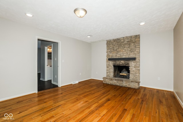 5060 Staughton Dr, Indianapolis, IN 46226 - unfurnished living room with wood finished floors, a stone fireplace, baseboards, and recessed lighting
