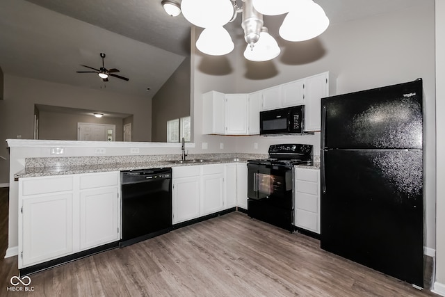 kitchen with vaulted ceiling, sink, black appliances, light hardwood / wood-style flooring, and white cabinetry