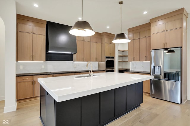 5469 Harness Dr, Greenwood, IN 46143 - kitchen featuring stainless steel appliances, a sink, wall chimney range hood, light wood-style flooring, and a center island with sink