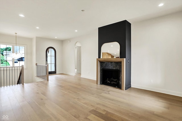 5469 Harness Dr, Greenwood, IN 46143 - unfurnished living room with arched walkways, light wood-style flooring, recessed lighting, baseboards, and a fireplace