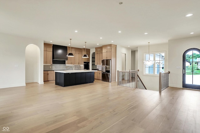 5469 Harness Dr, Greenwood, IN 46143 - kitchen featuring stainless steel refrigerator with ice dispenser, arched walkways, open floor plan, wall chimney range hood, and light wood finished floors
