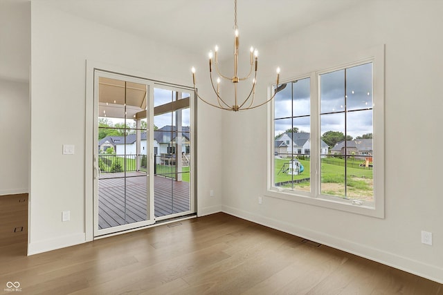 5469 Harness Dr, Greenwood, IN 46143 - unfurnished dining area with a chandelier, wood finished floors, and baseboards